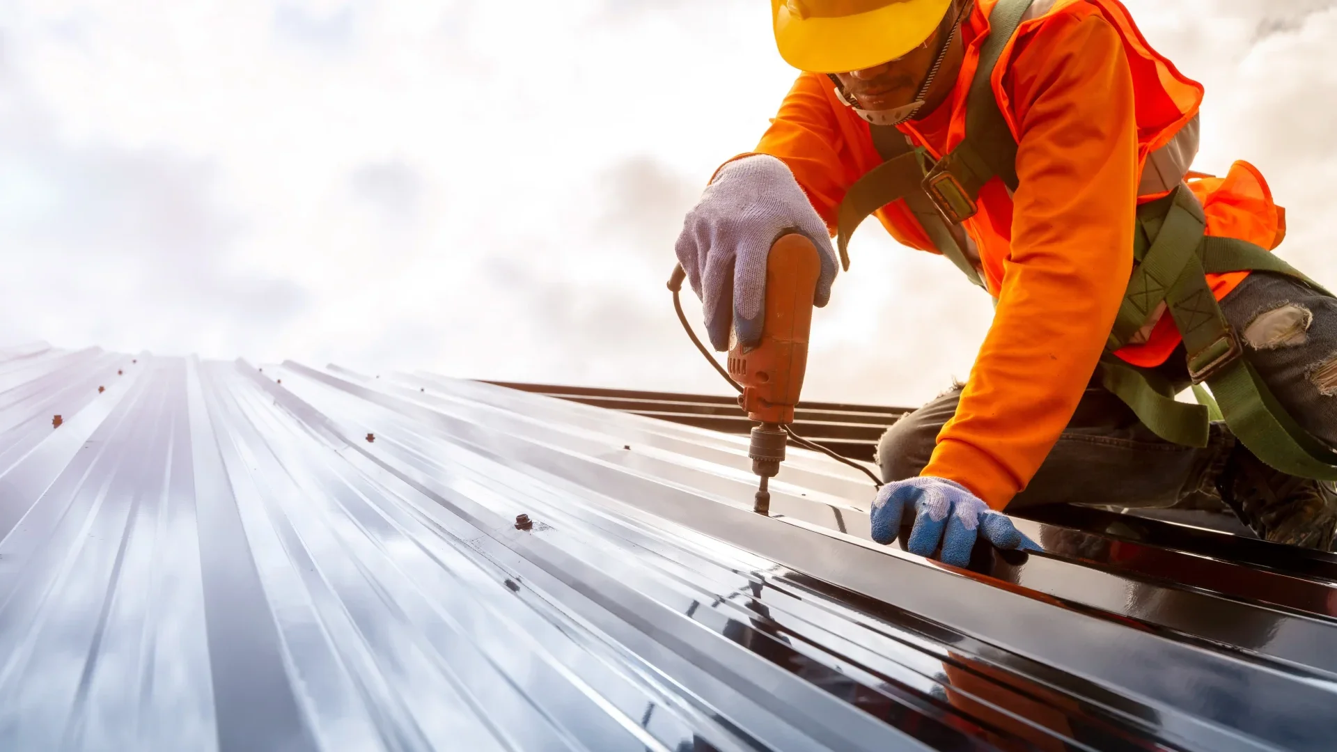 A technician uses a power drill to secure solar panels on the roof of a building during commercial roof repairs.