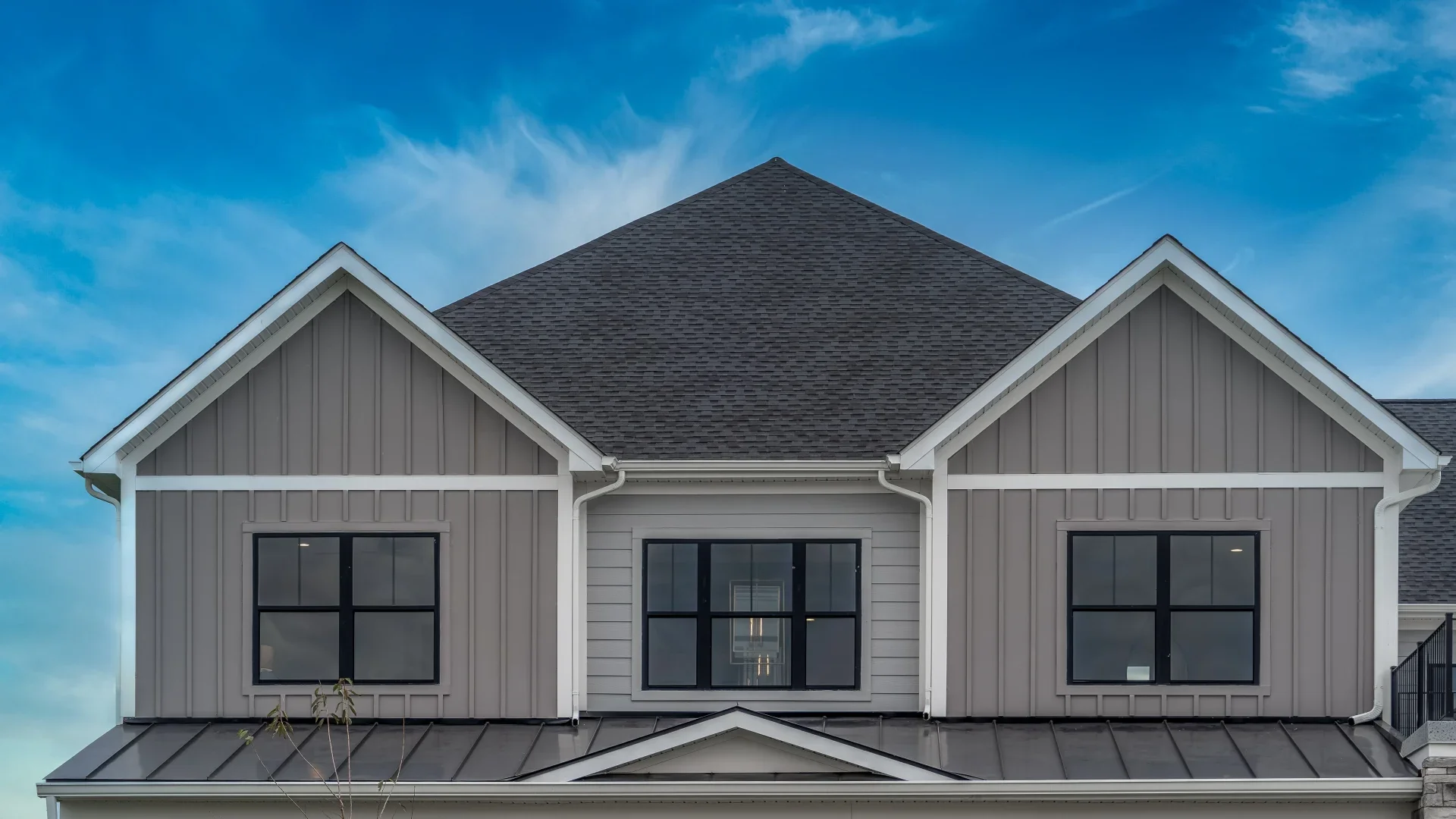 A sleek black standing-seam roof with skylights tops a modern wooden home, showcasing residential metal roofs.