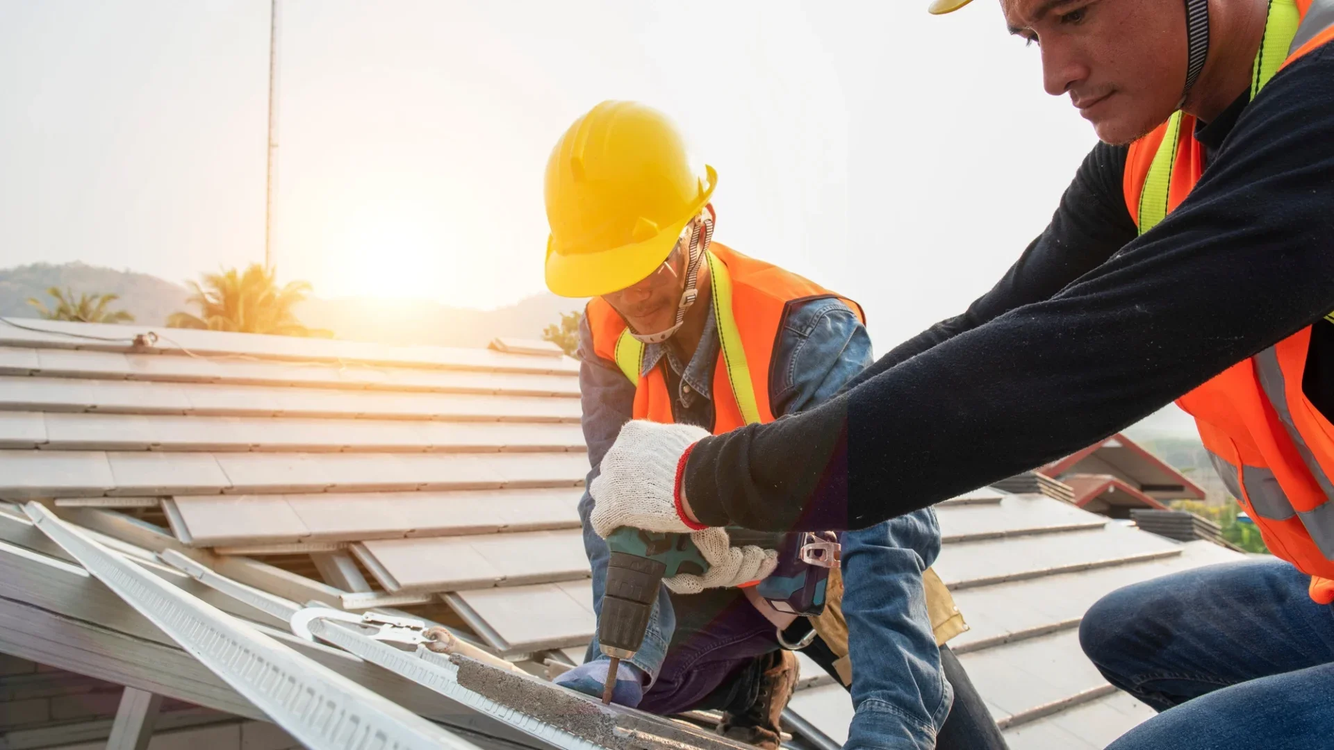 Two roofers working on metal roof