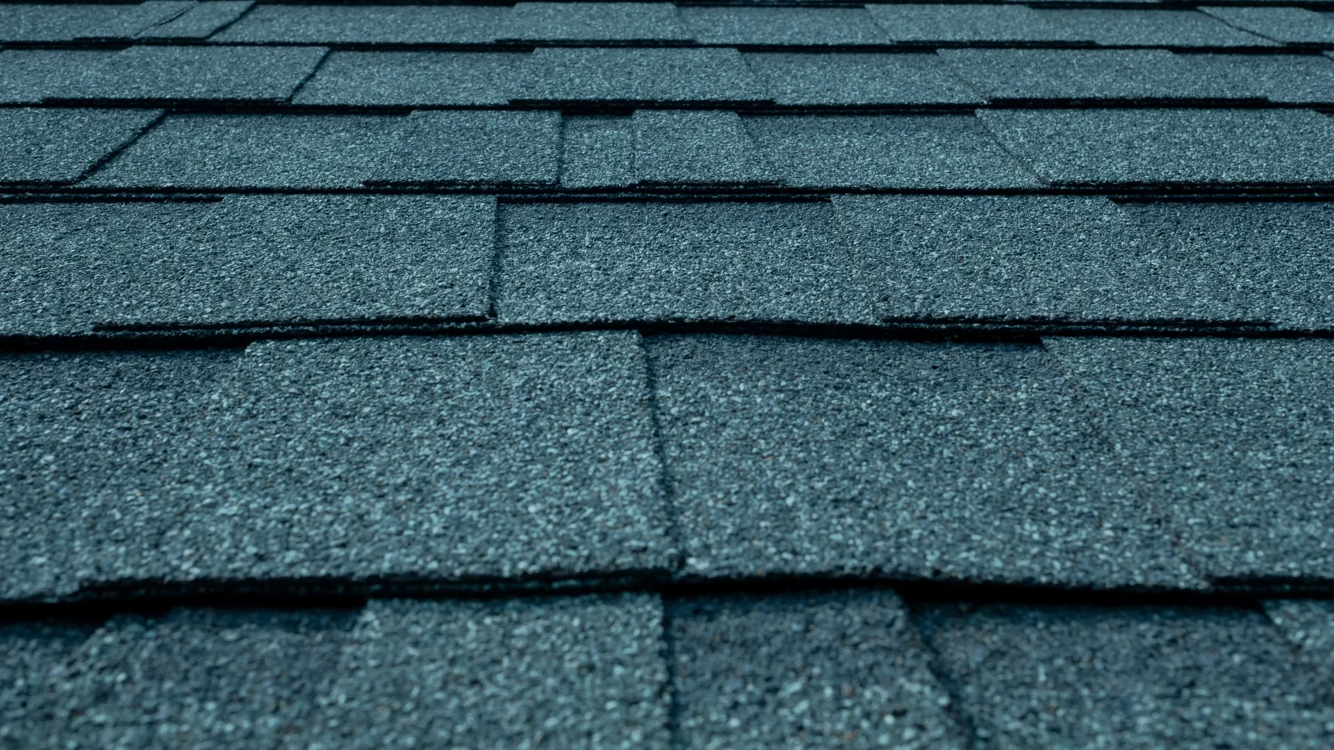 A close-up view highlights dark standing-seam panels on a wooden gable roof, showcasing modern residential metal roofs.